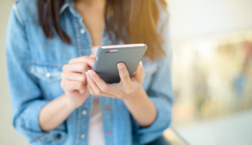 Girl in a Denim Jacket using a A smart phone 