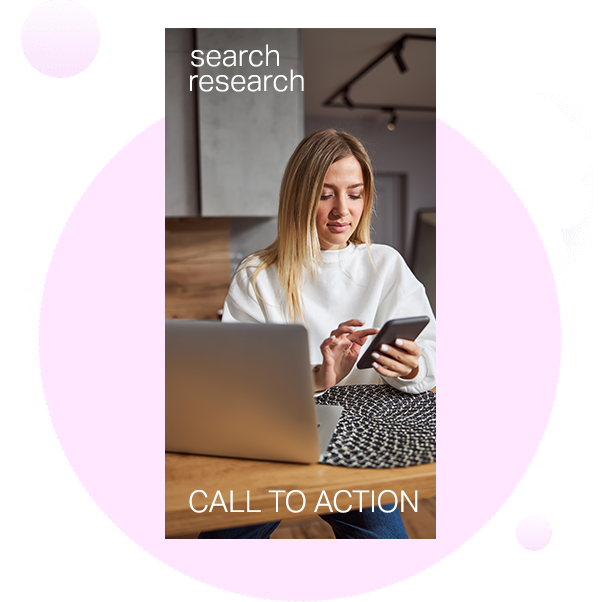 Woman sitting in her home with her laptop open while looking at her mobile phone